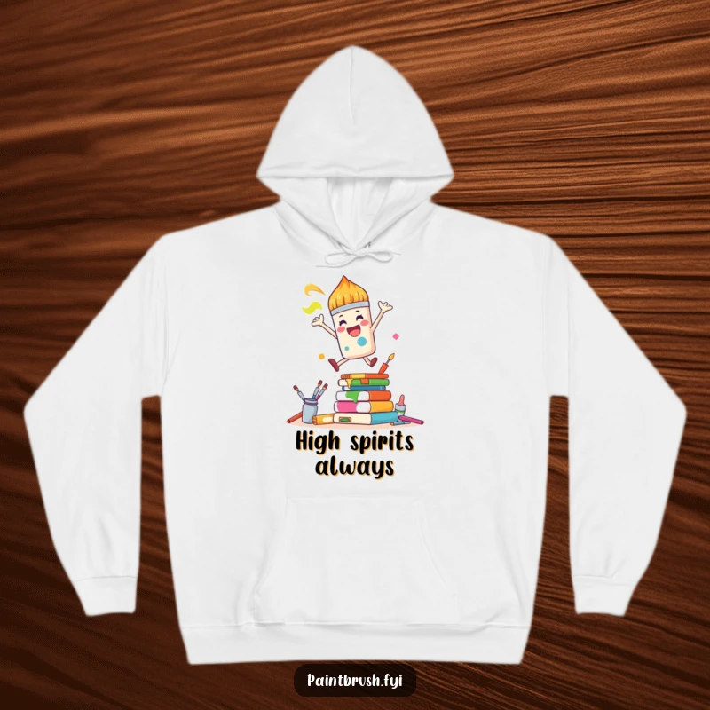 Funny Hoodie: A joyful paintbrush character leaps over colorful art supplies, offering cozy art vibes and humor.